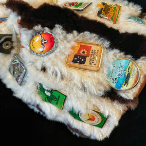 A 1980s KANGAROO SKIN POUCH DECORATED WITH TOURIST BADGES FROM THE N.T.