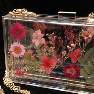 A PERSPEX CLUTCH WITH ENCASED WILD FLOWERS