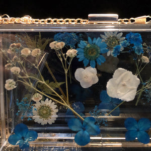 A PERSPEX CLUTCH WITH ENCASED WILD FLOWERS